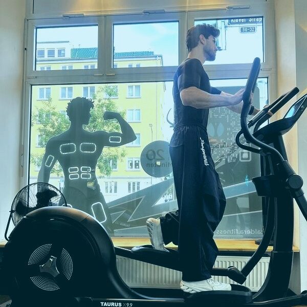 Kardio mit EMS: Mann trainiert auf dem Crosstrainer im EMS-Anzug