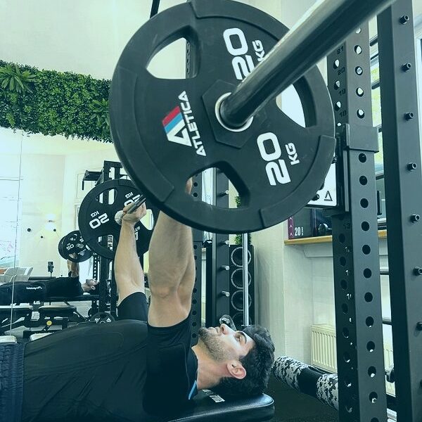 Krafttraining mit EMS: Mann trainiert Bankdrücken im EMS-Anzug im Fitnessstudio
