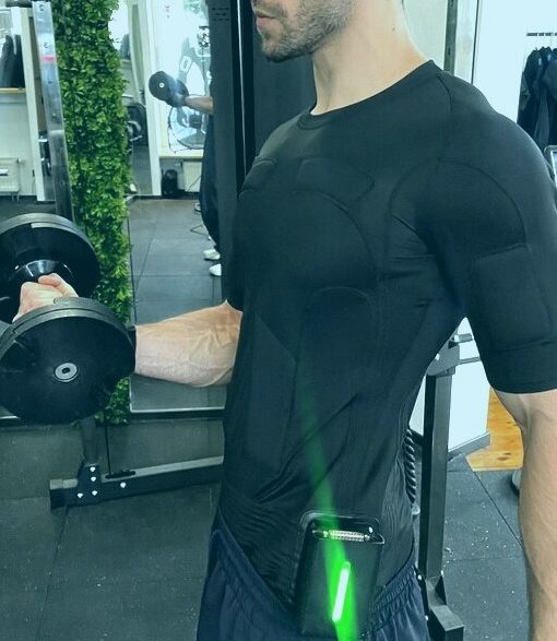 Mann im schwarzen EMS-Anzug beim Bizeps-Curl mit Kurzhantel im Fitnessstudio